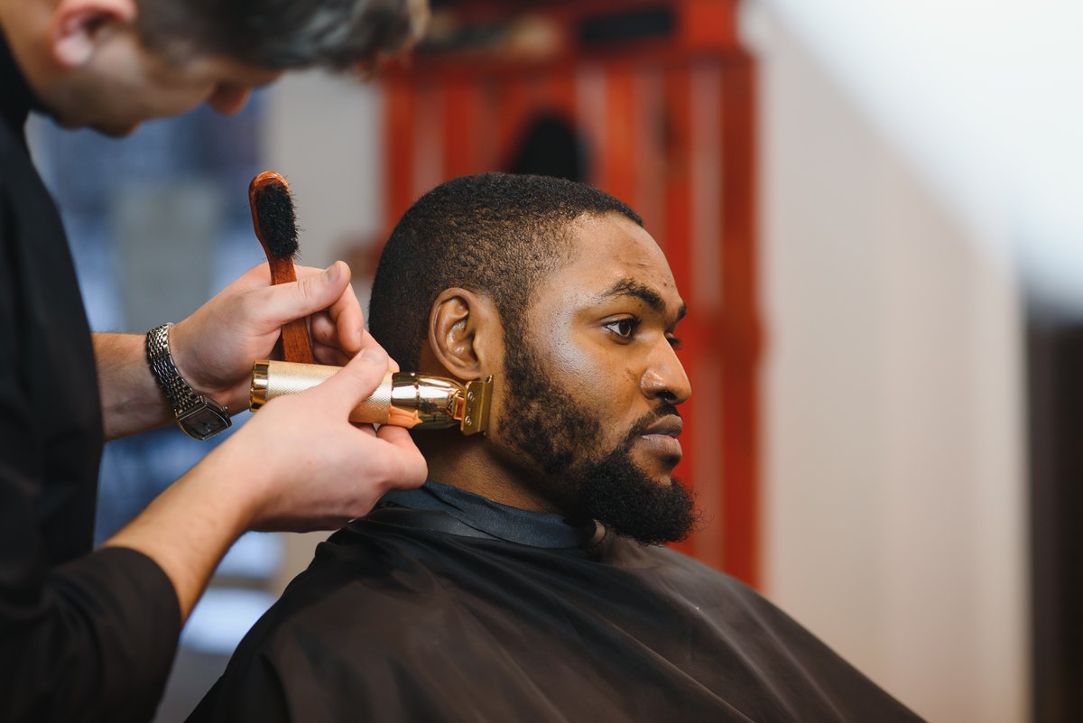 barber trimming a beard with clippers